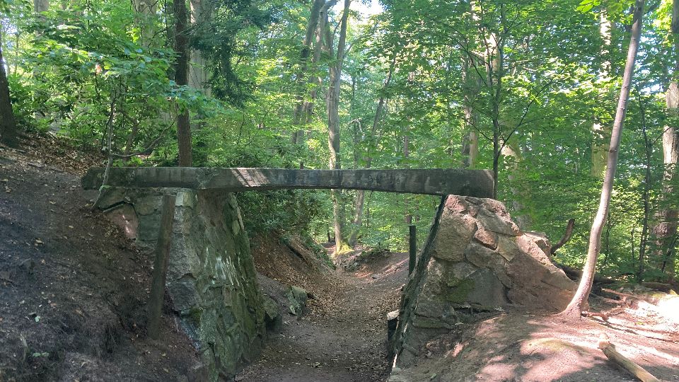 Waldabschnitt im Billetal mit historischen Steinbauten, die einen Durchgang auf einem Pfad bilden