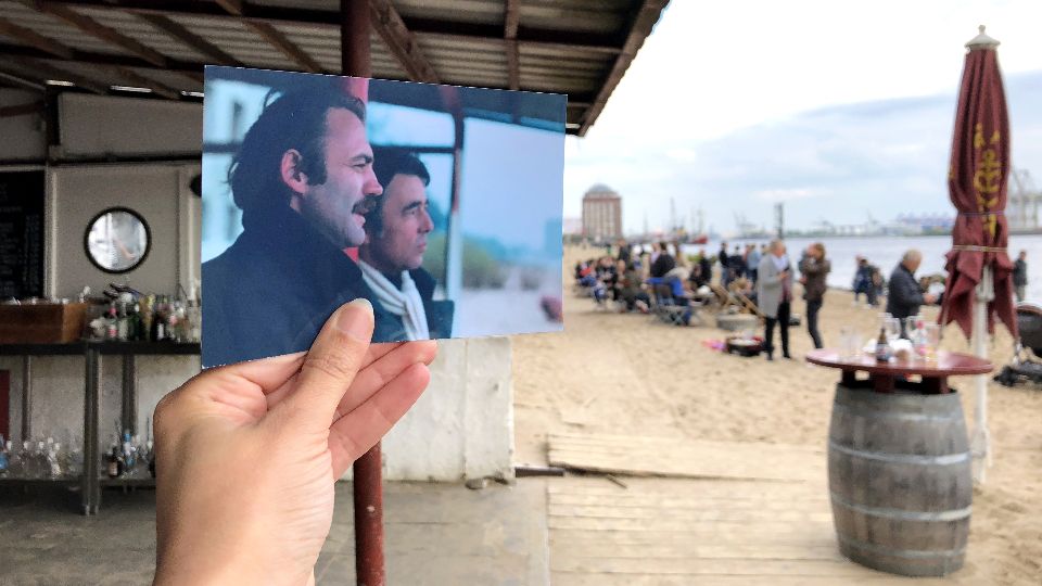 Ein Foto zeigt einen Auszug des Hamburg-Films Der Amerikanische Freund vor der Original Spielstätte am Cafe Strandperle am Elbstrand