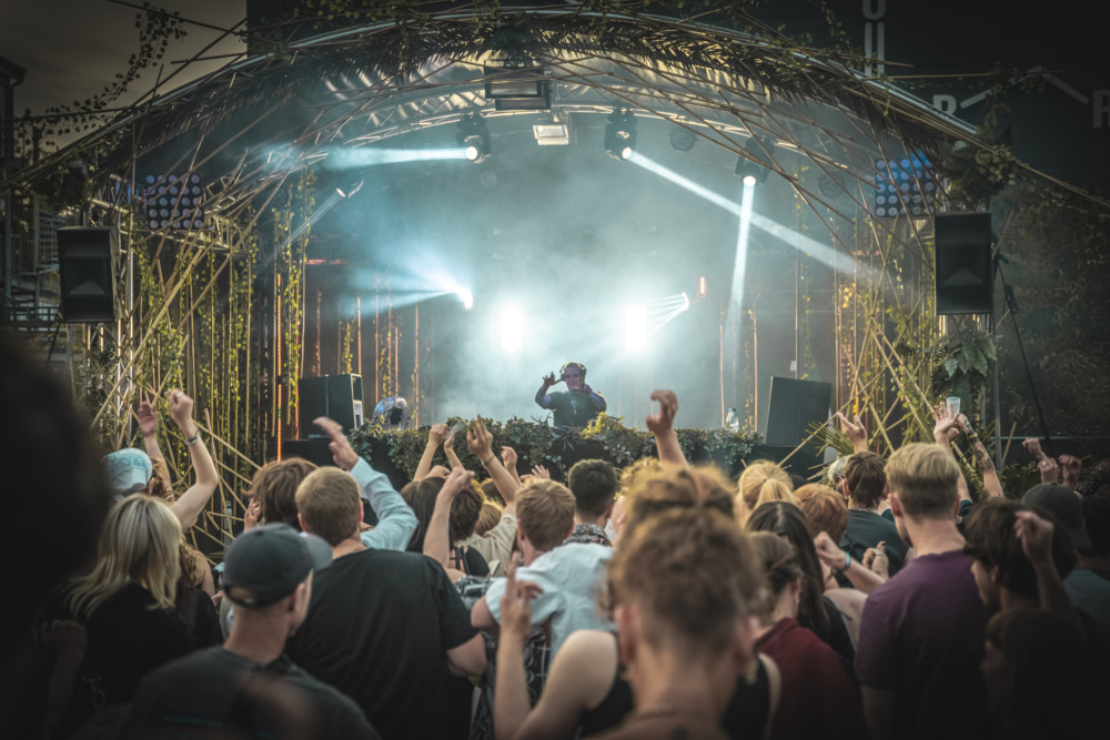 eine Menschenmenge tanzt unter freiem Himmel in einem techno club in hamburg vor einem DJ-Pult