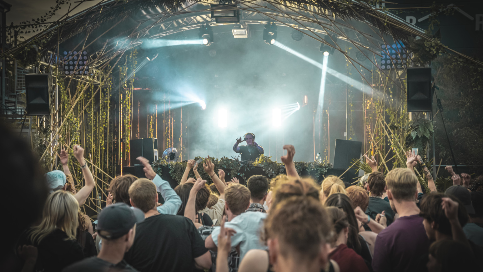 eine Menschenmenge tanzt unter freiem Himmel in einem techno club in hamburg vor einem DJ-Pult