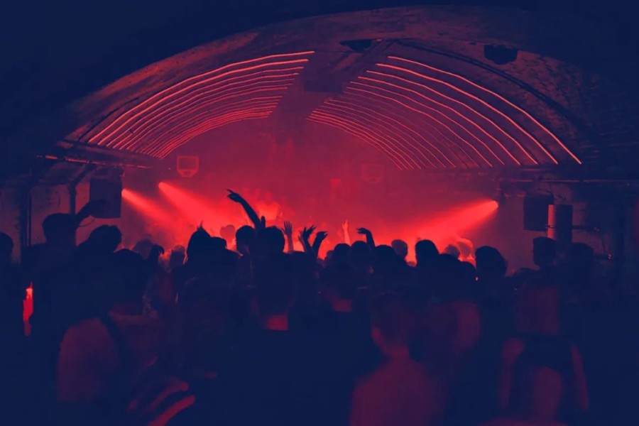 unkenntliche Menschenmenge tanzt in einem Techno Club in Hamburg in rotem Licht