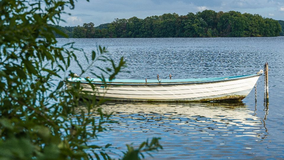 Ein leeres kleines Boot treibt auf dem ruhigen Plöner See, einem Ausflugsziel in Hamburgs Umland
