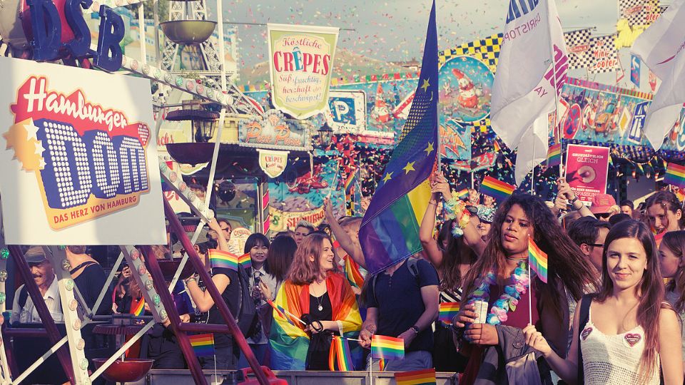 eine bunte Menschenmasse mit unzähligen Fahnen und Konfetti am Regenbogentag auf dem Hamburger Dom zur Pride Week