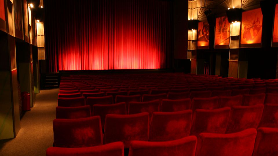 Blick über die Sitzreihen zur mit einem roten Vorhang verdeckten Leinwand im Zeise Kino in Hamburg