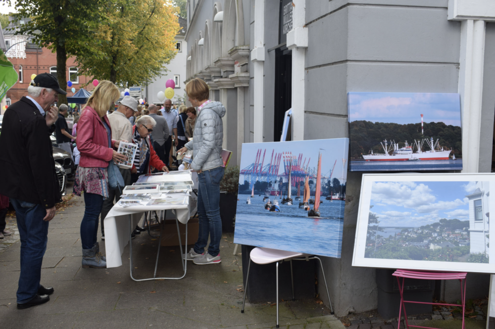 Leute schauen sich Kunst an einem Stand auf dem Blankeneserstraßenfest an. 