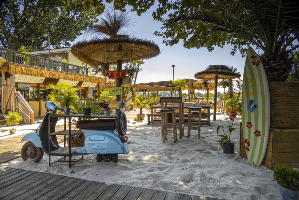 Ein echter Sandstrand mit Palmen und Loungemöbel aus Holz im 28Grad Strandbad Wedel 