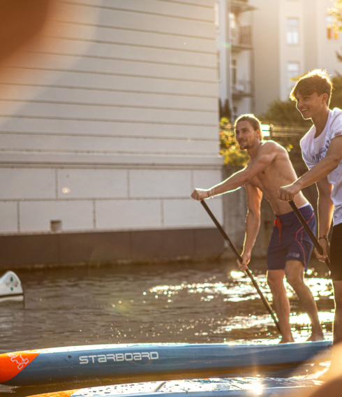 Zwei Männer, die auf Stand Paddleboards übers Wasser paddeln.