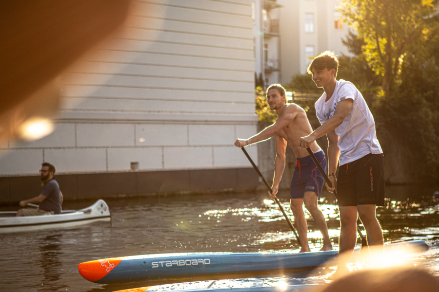 Zwei Männer, die auf Stand Paddleboards übers Wasser paddeln.