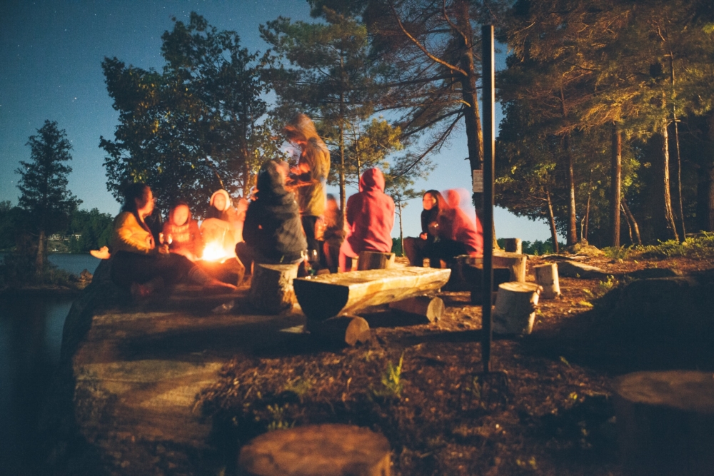 Campen im Wald nur eine Stunde mit dem Auto von Hamburg entfernt: Menschen sitzen um ein Lagerfeuer. 