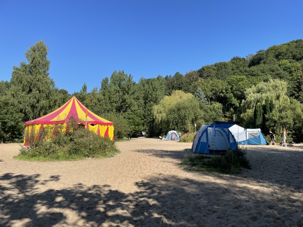 Zelte und ein Zirkuszelt im Sand beim Camping an Hamburgs Falkensteiner Ufer