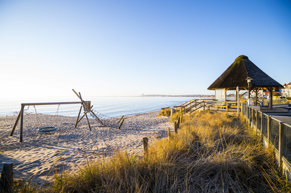 Strandabschnitt von Haffkrug rechts daneben ein Strandpavillon am Ende eines Stegs