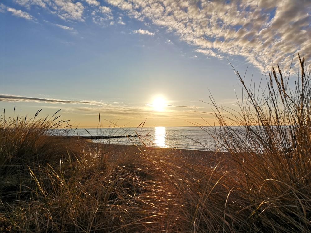 Sonne, die auf das Meer scheint, davor der Strand von Rettin, ein beliebtes Ausflugsziel an der Ostsee.