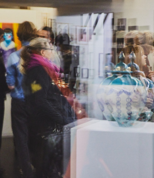 Menschen stehen während einer Ausstellung in einer Galerie und betrachten Kunst