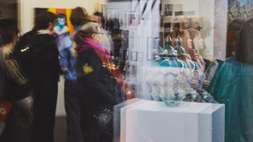 Menschen stehen während einer Ausstellung in einer Galerie und betrachten Kunst