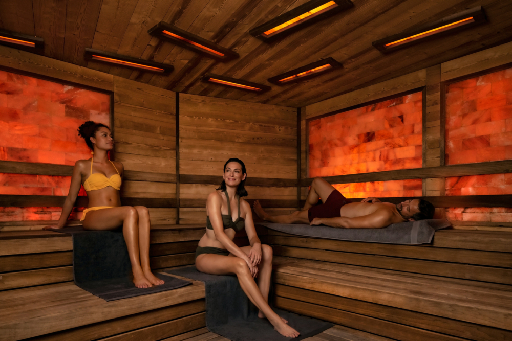 Drei Menschen sitzen in einer Sauna von Bäderland Hamburg auf Holzbänken