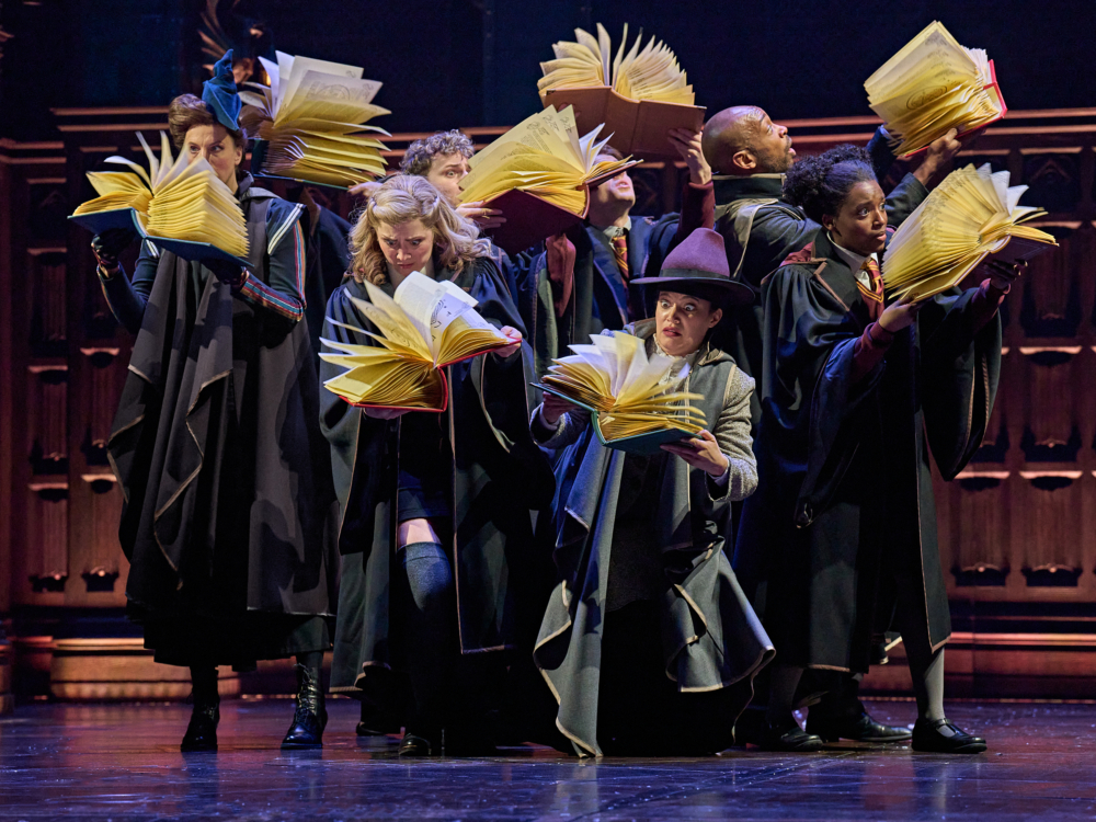 Zauberer aus dem Harry Potter Musical in schwarzen Roben mit geöffneten Büchern 