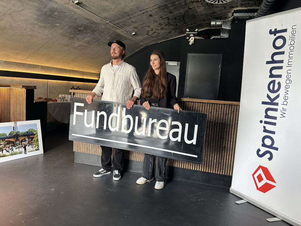 Die Besitzer des Fundbureau mit einem Schriftschild in den Händen