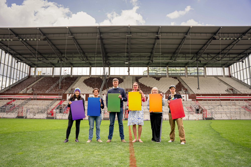 Menschen stehen im Millerntor-Stadion und halten bunte Solarzellen hoch.