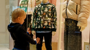 Ein kleiner Junge steht am Schaufenster und betrachtet die Auslagen