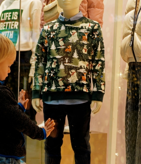 Ein kleiner Junge steht am Schaufenster und betrachtet die Auslagen