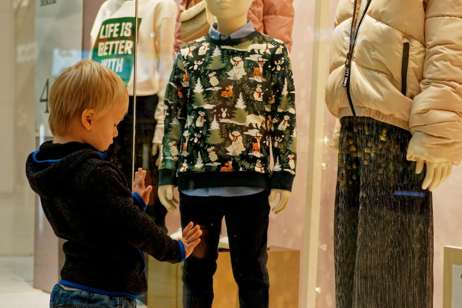 Ein kleiner Junge steht am Schaufenster und betrachtet die Auslagen