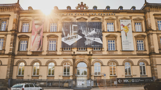 Das MK&G von Außen in der Frontalansicht. Ein großes Altbaugebäude in der Stadt