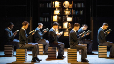 7 Personen auf Stühlen aus Büchern am lesen