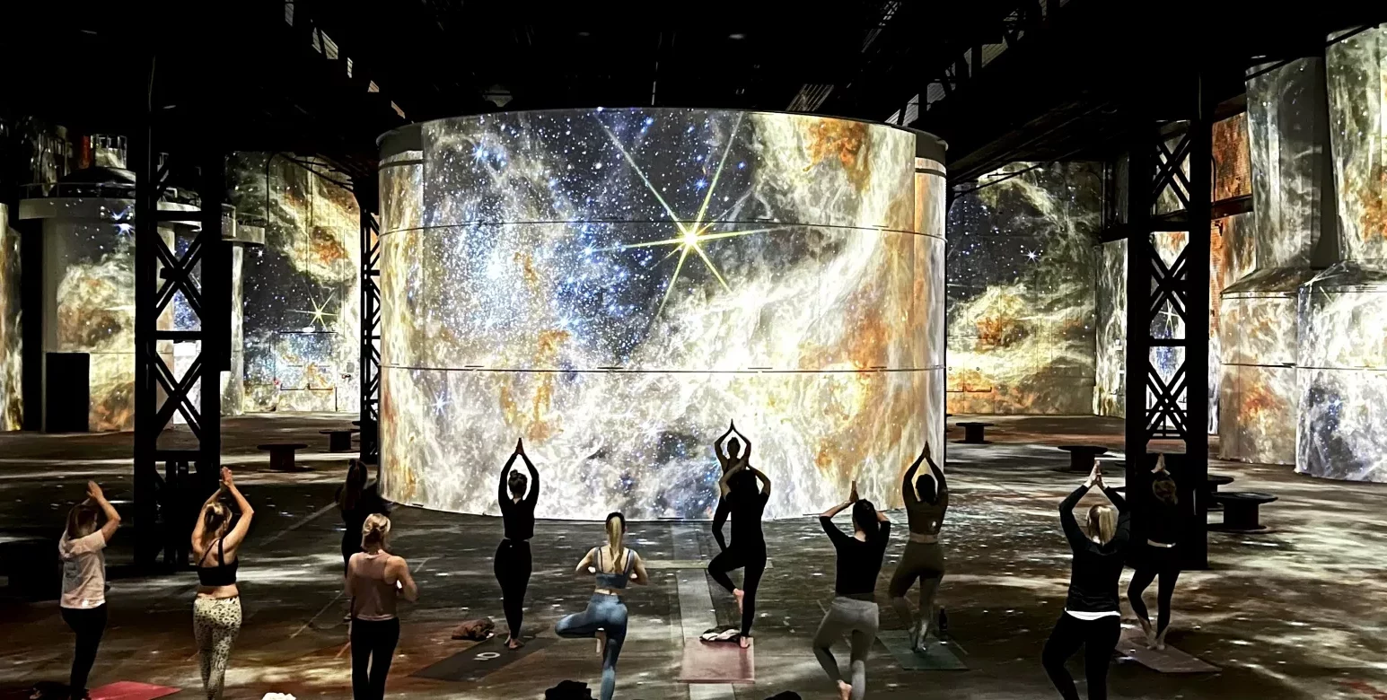 Personen die Yoga machen vor Universums-Projektionen