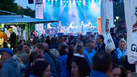 Menschenmenge vor einer Bühne auf der eine Band spielt