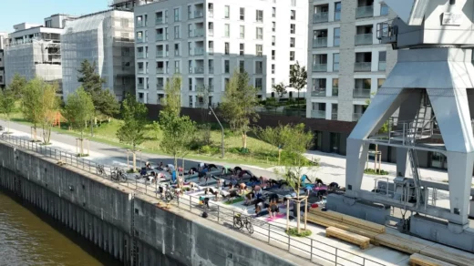 Personen die Yoga am Wasser machen vor einer Häuserwand