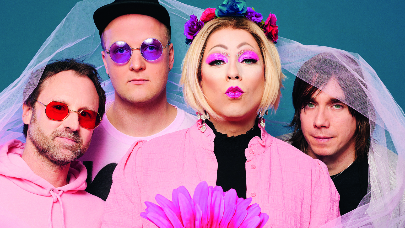 Vier pink gekleidete Personen mit einer großes ebenfalls pinken Blume in der Hand