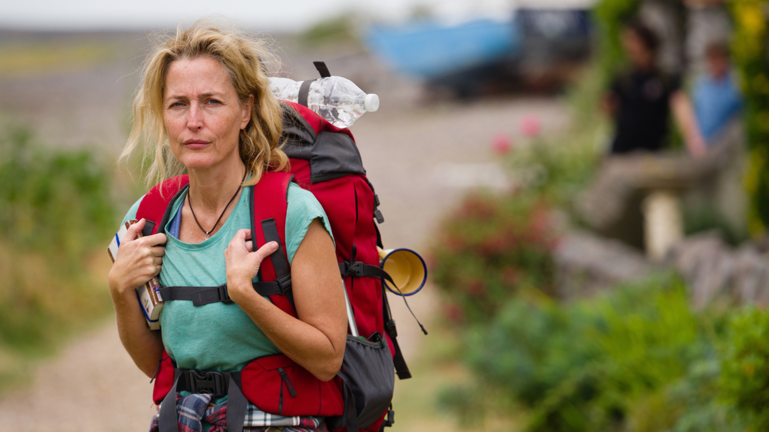 Schauspielerin Gillian Anderson mit Rucksack vor einer weiten, hügeligen Steppe