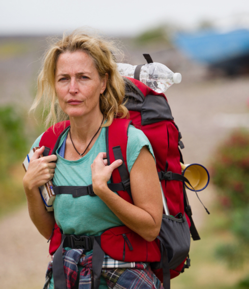 Schauspielerin Gillian Anderson mit Rucksack vor einer weiten, hügeligen Steppe