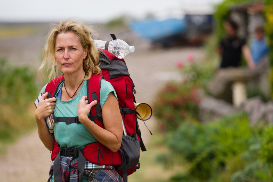 Schauspielerin Gillian Anderson mit Rucksack vor einer weiten, hügeligen Steppe