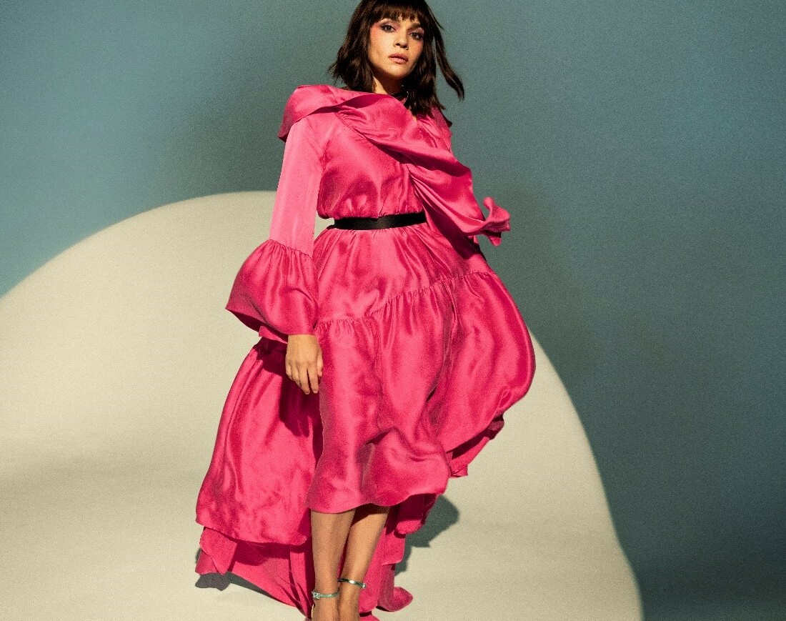 Norah Jones in einem roten Kleid vor einem blauen Hintergrund