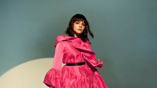 Norah Jones in einem roten Kleid vor einem blauen Hintergrund