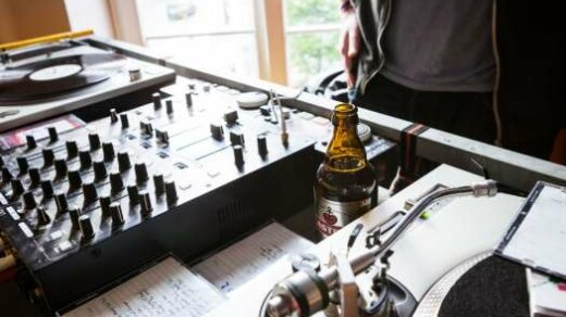 Ein Tisch mit Mischpult, Kopfhörern, einem Bier und Zetteln im Close-Up