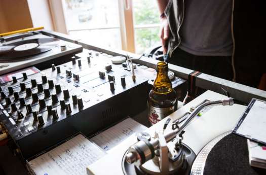 Ein Tisch mit Mischpult, Kopfhörern, einem Bier und Zetteln im Close-Up