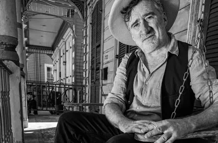 Ein Bild von Jon Cleary im Sitzen vor einem alten Gebäude