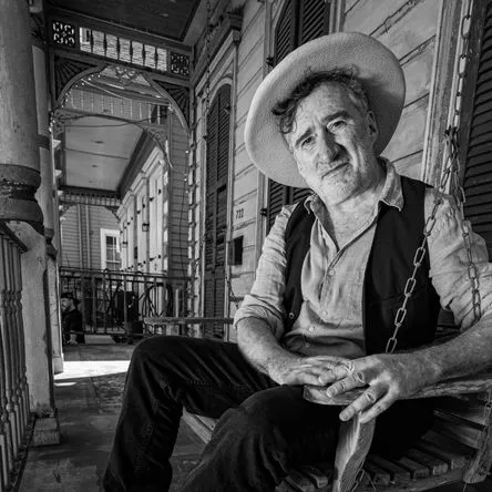 Ein Bild von Jon Cleary im Sitzen vor einem alten Gebäude