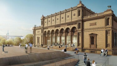 Historisches Gebäude mit Arkaden und Säulen, davor Menschen auf einem Platz bei klarem Himmel