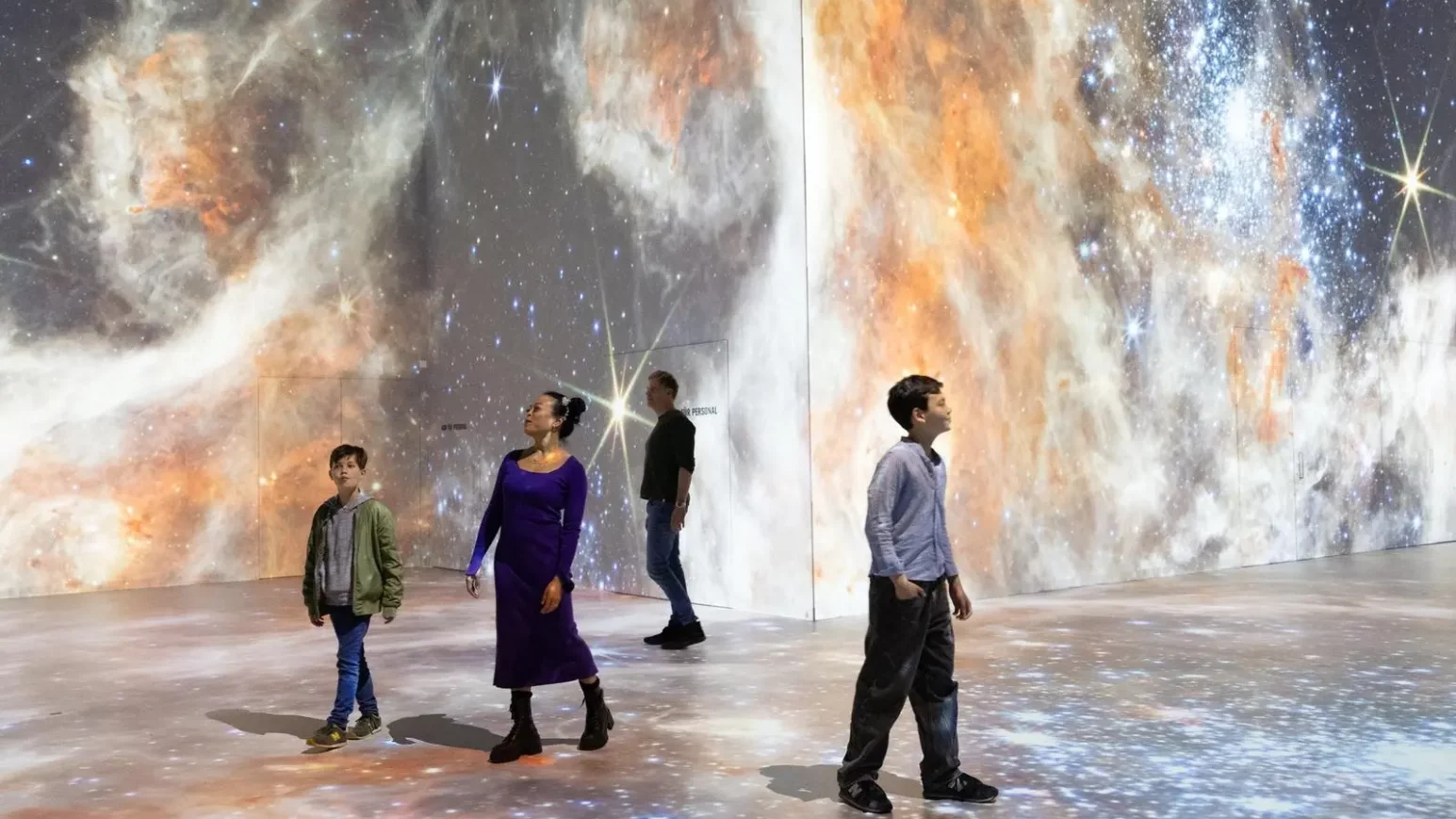 Personen in einem ausgeleuchtet Raum, der aussieht wie eine Galaxie