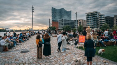Menschen auf einem Platz an der Elbe vor der Elbphilharmonie