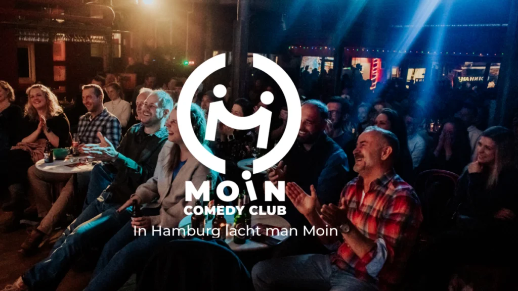 Leute im Hintergrund in einem Club und Zentral ein Logo von Moin Comedy Club Show
