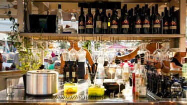 Bar mit Regalen voller Weinflaschen und Gläsern, Theke mit Saft und Dekoration