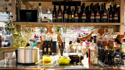 Bar mit Regalen voller Weinflaschen und Gläsern, Theke mit Saft und Dekoration