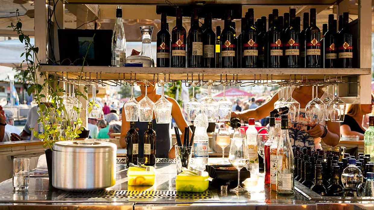 Bar mit Regalen voller Weinflaschen und Gläsern, Theke mit Saft und Dekoration