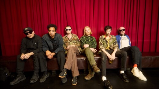 Ein Bild der Band "Warmduscher" auf einem Sofa vor einem roten Vorhang