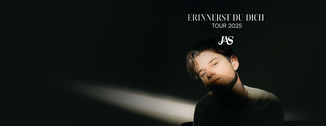 Mann mit dunklem Pullover sitzt im Lichtkegel vor schwarzem Hintergrund. Text darüber: 'ERINNERST DU DICH TOUR 2025 JAS'.