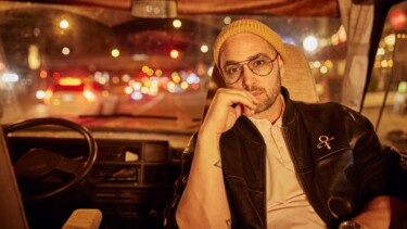 Eine Person in einem Auto bei Nacht mit Straßenlicht, das durch die Scheibe reinkommt.